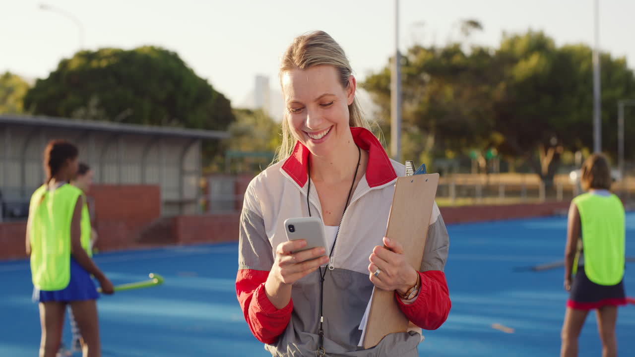 entrenador de hockey sonriente enviando mensajes de texto por teléfono