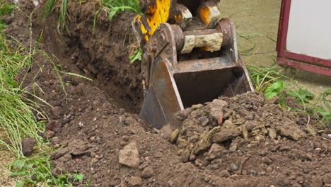 excavator bucket digging on the ground. - closeup shot