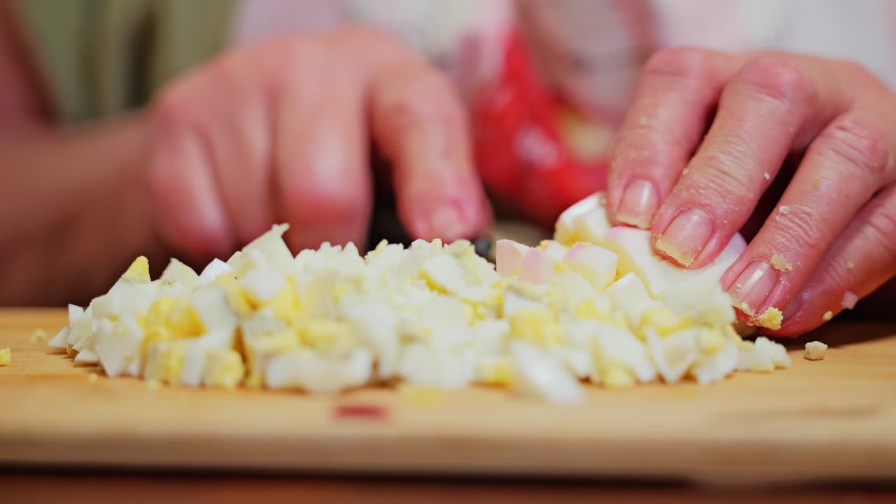 Close-up of hands slicing boiled eggs on cutting board for homemade egg salad