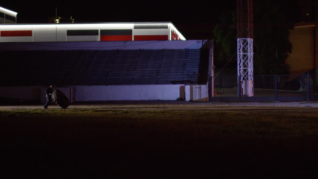 밤 에 경기장 밖 의 타이어 근처 에 있는 사람