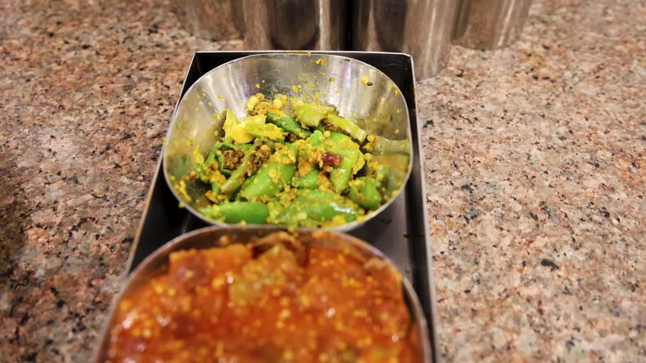 Primer plano de platos indios picantes con cucharones en recipientes metálicos tradicionales