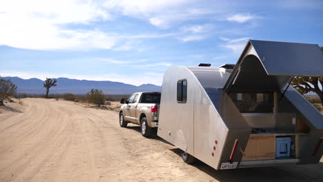 A-metal-teardrop-travel-trailer-tiny-house-camping-in-the-epic-California-desert-with-scenic-mountains-and-Joshua-trees