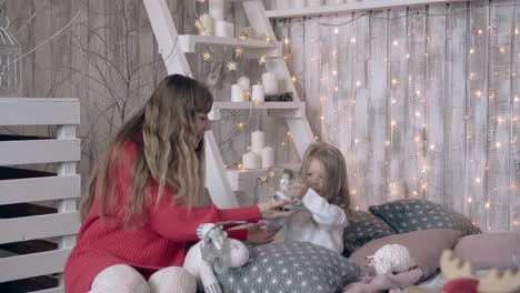 mum in red dress sweater plays toys with toddler girl