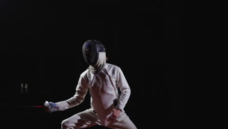 a fencer wearing a mask and white uniform stands in a fencing stance, holding a foil.