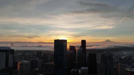 golden sunrise over a seattle cityscape with a view of mt rainer, circling aerial