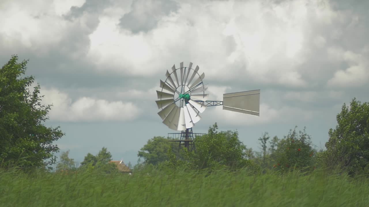 물과 갈대 근처에 있는 네덜란드의 오래된 미국 풍차, 바람에 흔들리는 슬로모션의 작은 인형