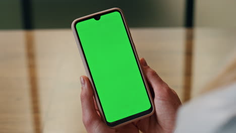 teléfono de pantalla verde mujer con las manos en la oficina de cerca. persona mirando la pantalla