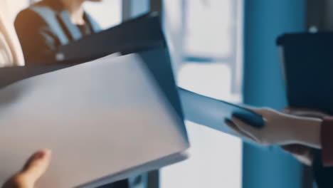 business professionals exchanging documents and folders in an office setting