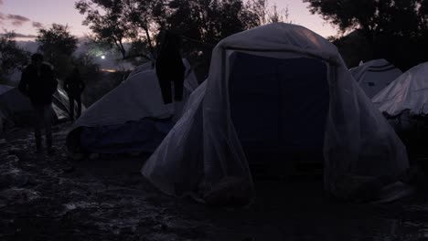 A-refugee-silhouetted-at-dusk-walks-around-tents-Moria-Refugee-Camp