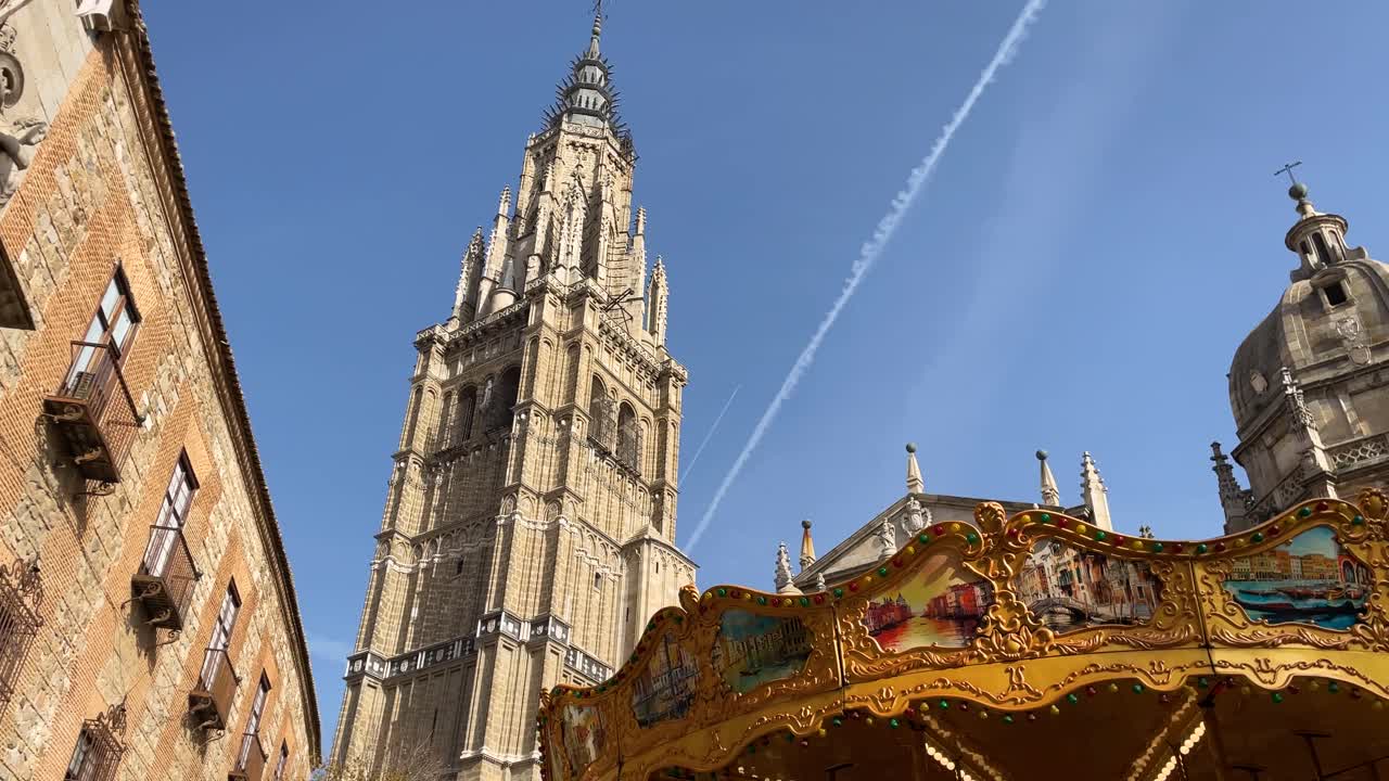 filming in a Plaza de Toledo where the upper parts of the Bishop's House appear followed by the bell tower of the cathedral, the golden roof of a carousel and followed by another tower with a dome