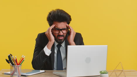 tired indian business man suffering from headache problem tension migraine stress at home office