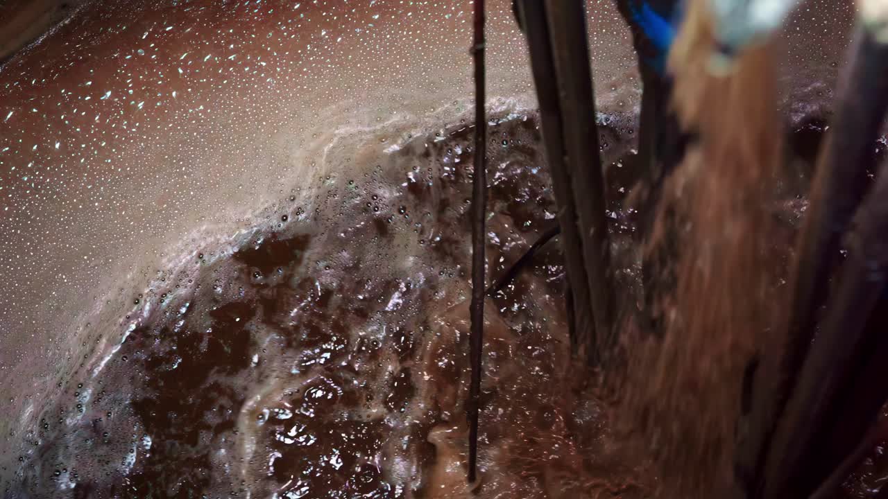 Close-up of industrial mixing with moving liquid and metal rods