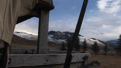 the camera looks through an opening in a covered wagon for a view of the mountains beyond