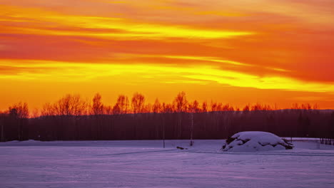 Snowy-landscape-timelapse-under-an-intense-orange-sky-contrasted-with-clouds