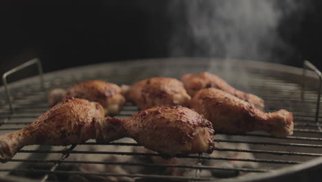 chicken drum sticks grilled on coal and fire with smoke coming up with black background shot raw and 4k eye level