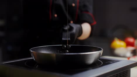 el chef vertiendo aceite en una sartén