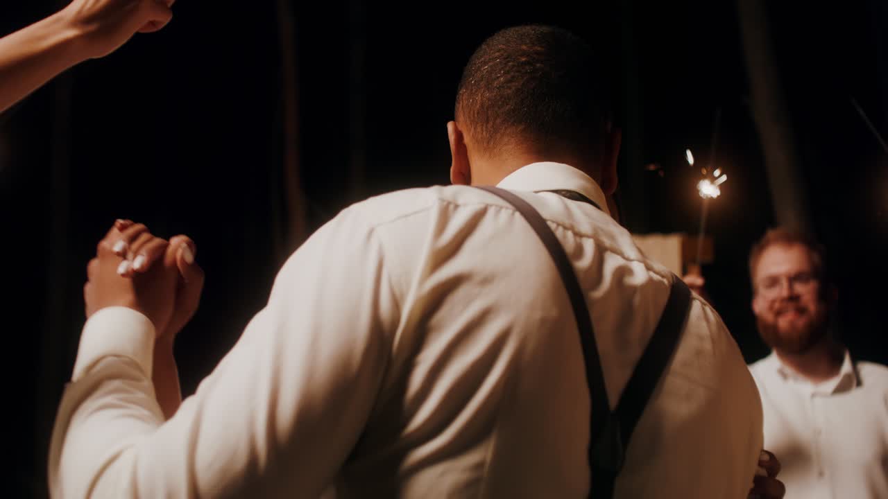 커플이 스파클러와 함께 야간 행사에서 춤을 춘다