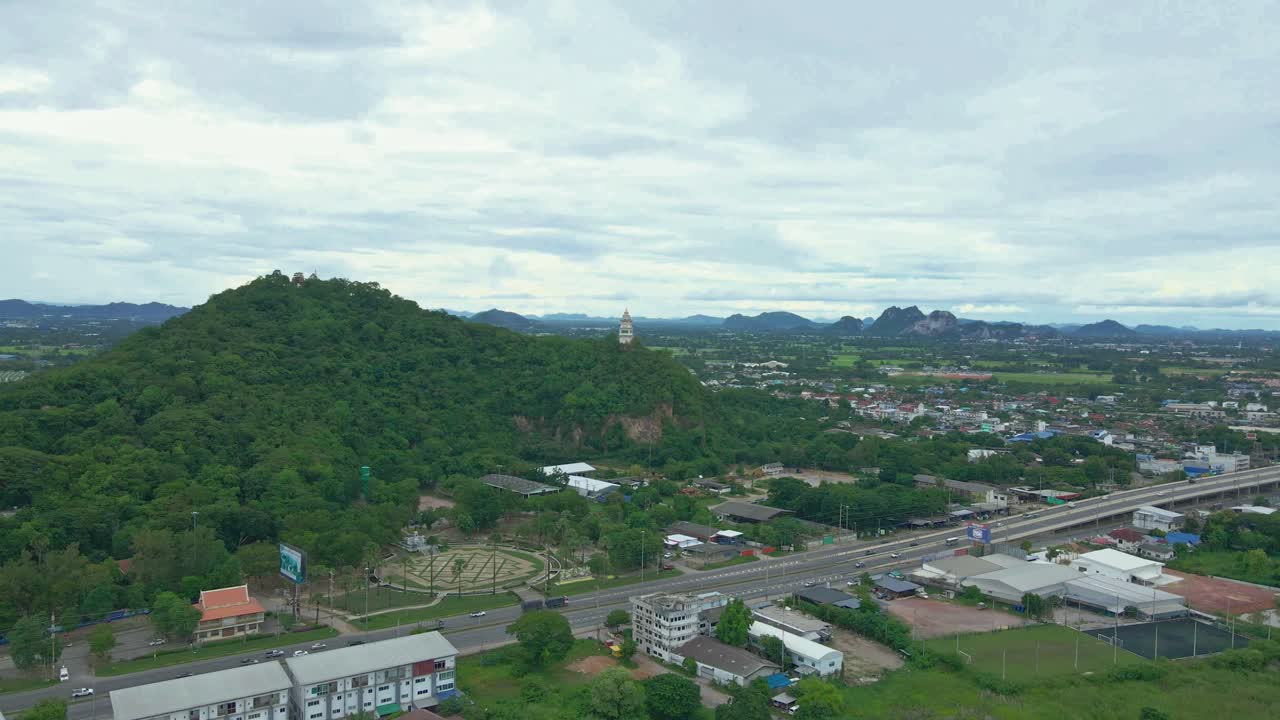 drone aéreo panorámico sobre autopista con torre del reloj en la ladera de la colina en tailandia cerca del templo de khao kaen chan