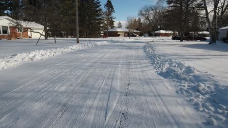 a forward driver's point of view of a snow covered residential neighborhood road.
