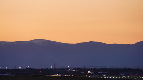 massive passenger jet descending gracefully toward runway, silhouetted against vibrant sunset colors with mountain landscape creating dramatic scenic backdrop