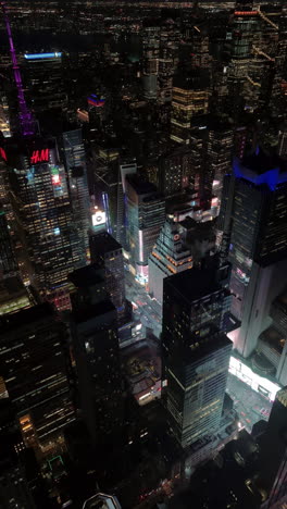vertical drone shot around the illuminated times square, night-time in new york