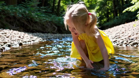young girl playing in a forest stream