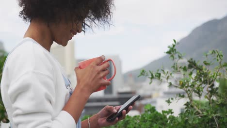 Mixed-race-woman-drinking-coffee-on-rooftop