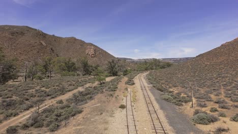 flight along the old railway tracks in the outback during summer midday australia amongst hilly dry landscape