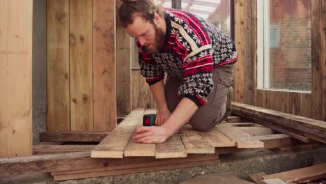 Mann-Befestigt-Holzbretter-Mit-Schraube-Mithilfe-Eines-Akku-Bohrers-Auf-Gewächshausboden