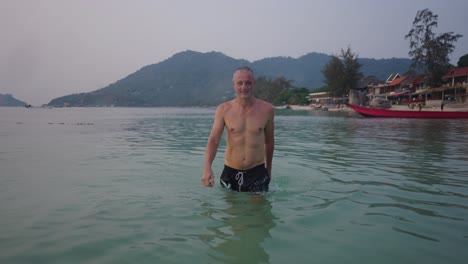 man emerges from the water at a tropical beach