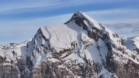 drone approaching the summit of fronalpstock mountain in the swiss pre-alps, showcasing the blend of rock and snow