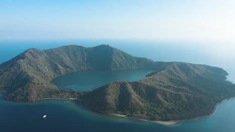 Excelente-Toma-Aérea-De-La-Isla-Satonda-Y-La-Pequeña-Masa-De-Agua-Que-Rodea-En-Indonesia