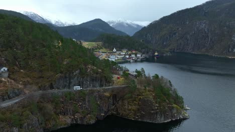 minibús blanco que se acerca a la aldea de stamneshella en noruega durante la primavera, aéreo