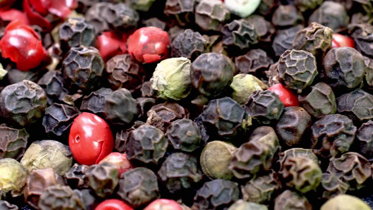 una pila de granos de pimienta multicolores secos mezclados, especias saladas girando lentamente.