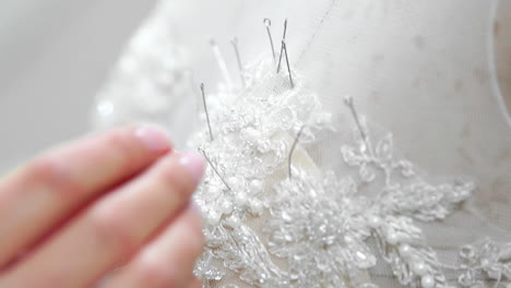 close-up fashion designer for brides in his studio pins needles lace wedding dress. seamstress creates an exclusive wedding dress. secure with pins and needles outline. small private business
