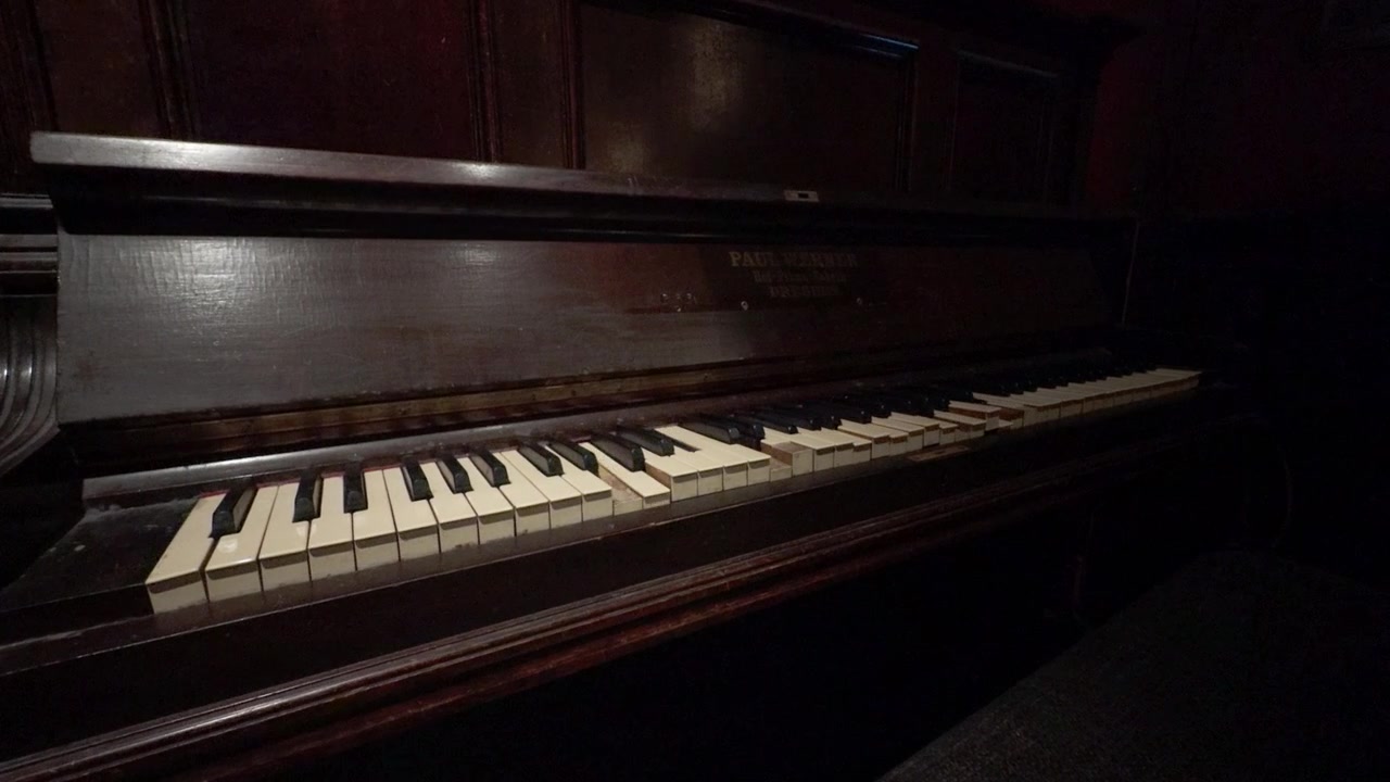 Primo piano 4K, pianoforte vintage con tasti d'avorio in movimento in una stanza di una villa infestata. Questo strumento meccanico crea un'atmosfera inquietante e soprannaturale per film horror, mistero o d'epoca