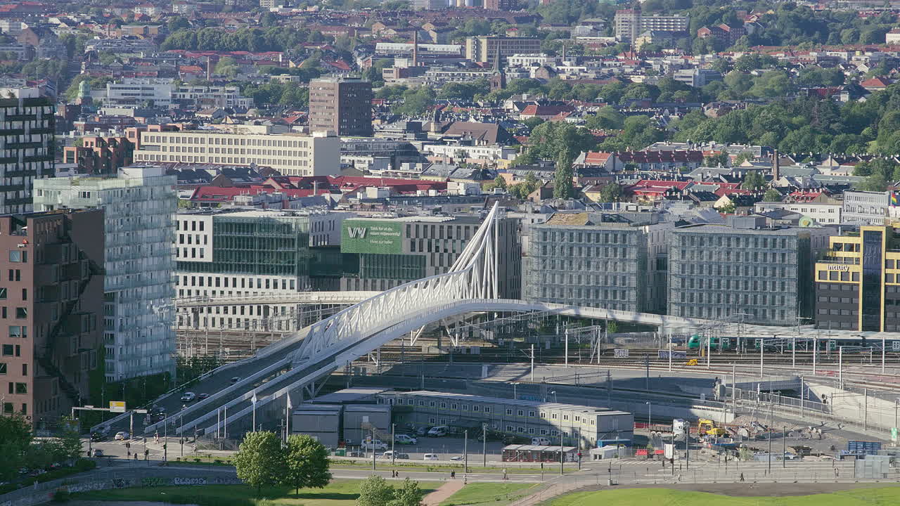 White steel bridge over railway tracks surrounded by urban architecture and city view. Filmed at Barcode in Oslo, Norway.