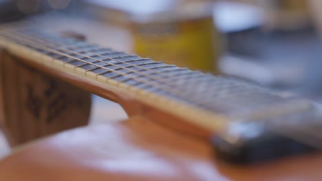 slow motion footage panning down the length of the neck of a guitar that has strings on it.