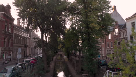 Vista-Aérea-Hacia-Atrás-Temprano-En-La-Mañana-Del-Canal-Del-Nieuwe-Gracht-En-La-Ciudad-Holandesa-Medieval-De-Utrecht-Justo-Por-Encima-Del-Nivel-De-La-Calle-Superior-Que-Revela-Bicicletas-Estacionadas-En-El-Puente-En-Primer-Plano