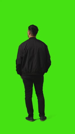 Vertical-Video-Rear-Full-Length-Portrait-Shot-Of-Bored-Or-Fed-Up-Man-Standing-And-Waiting-Against-Green-Screen