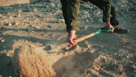 Man-use-spade-to-dig-hole-in-sandy-desert-soil,-closeup-low-angle