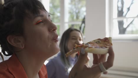 close up of two happy girls drinking wine and sharing pizza at home