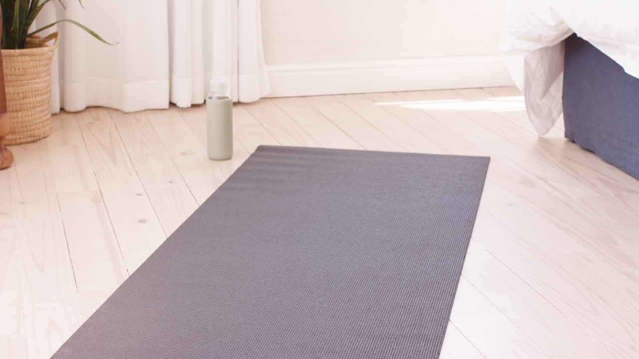 Yoga mat and water bottle on wooden floor in bright, peaceful room