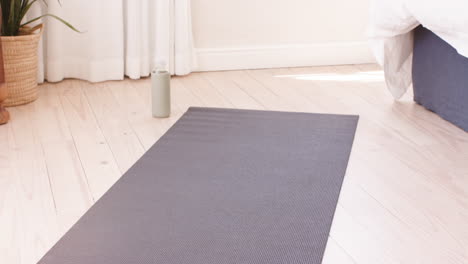 yoga mat and water bottle on wooden floor in bright, peaceful room