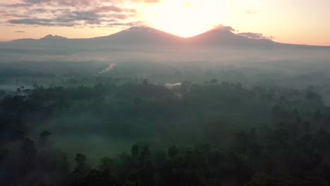 descending drone flight over the mountains surrounding the borobudur temple in indonesia at sunrise