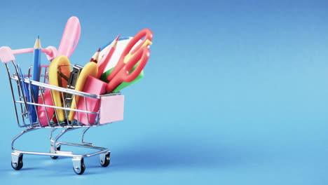 acercamiento del carrito de compras con artículos escolares y espacio de copia sobre fondo azul