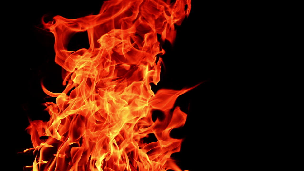 Flame of a campfire leaning to the side. Isolated bonfire burning at night. Close up.