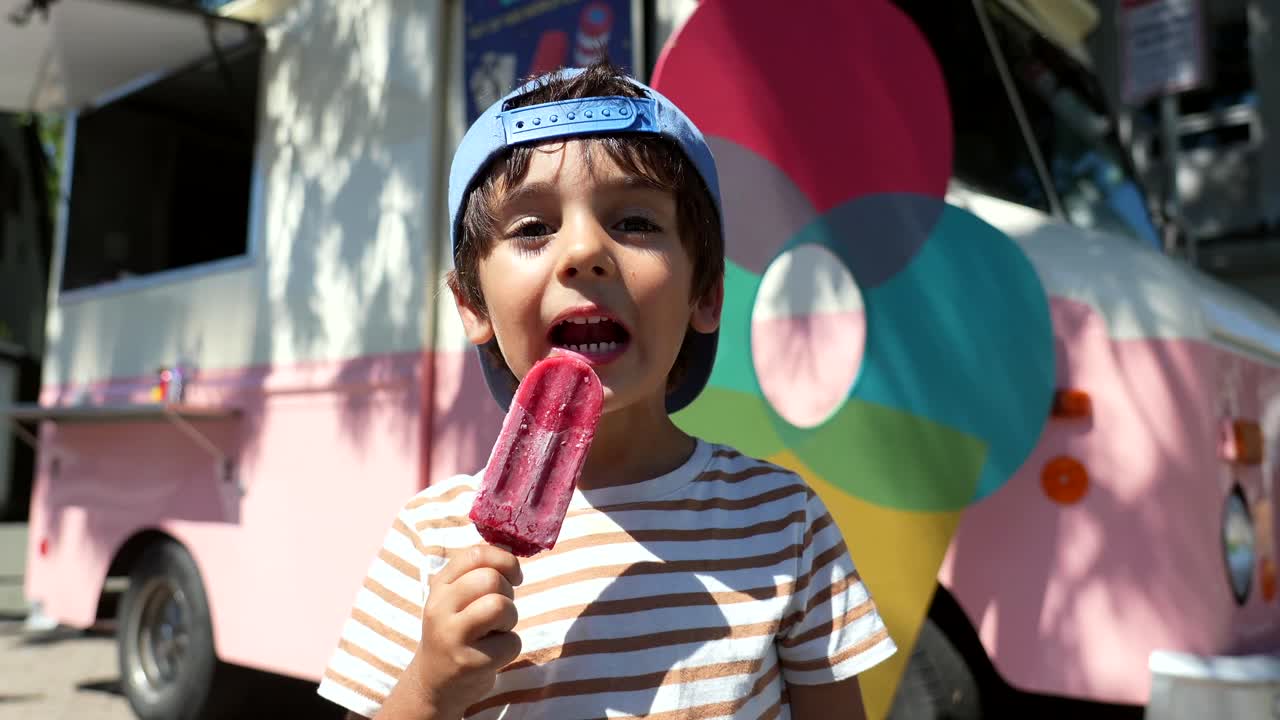 Bambino che gusta un ghiacciolo vicino al furgoncino dei gelati