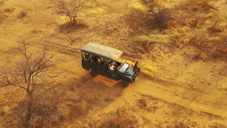 excelente vista aérea de un jeep safari que viaja por las llanuras de áfrica en la reserva de caza de erindi, namibia, con un guía nativo de observación tribal de san sentado en la parte delantera observando la vida silvestre 2