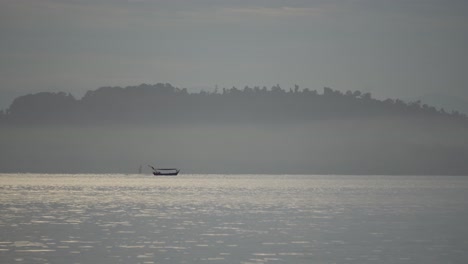 Un-Barco-Se-Mueve-En-El-Mar-Con-Una-Montaña-De-Fondo.